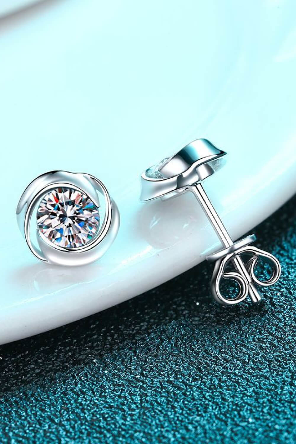 Silver orbital halo crystal stud earrings with a swirling design.