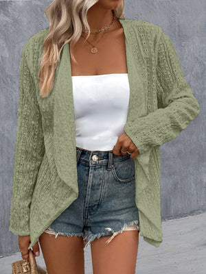 Sage open-weave cardigan with draped front and long sleeves, styled with a white tube top and denim shorts.