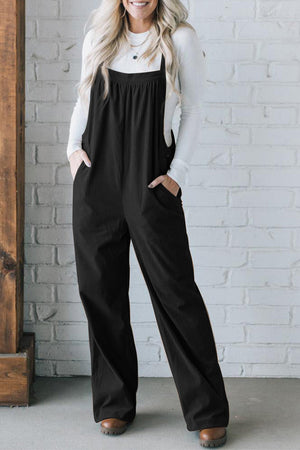 Black corduroy wide-leg overalls with pockets, styled with a white long-sleeve top.