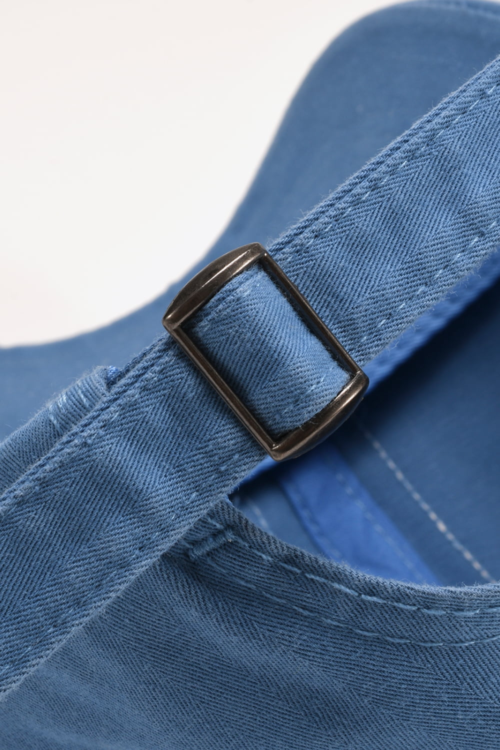 Cobalt blue denim baseball cap with adjustable strap and metal buckle detail.