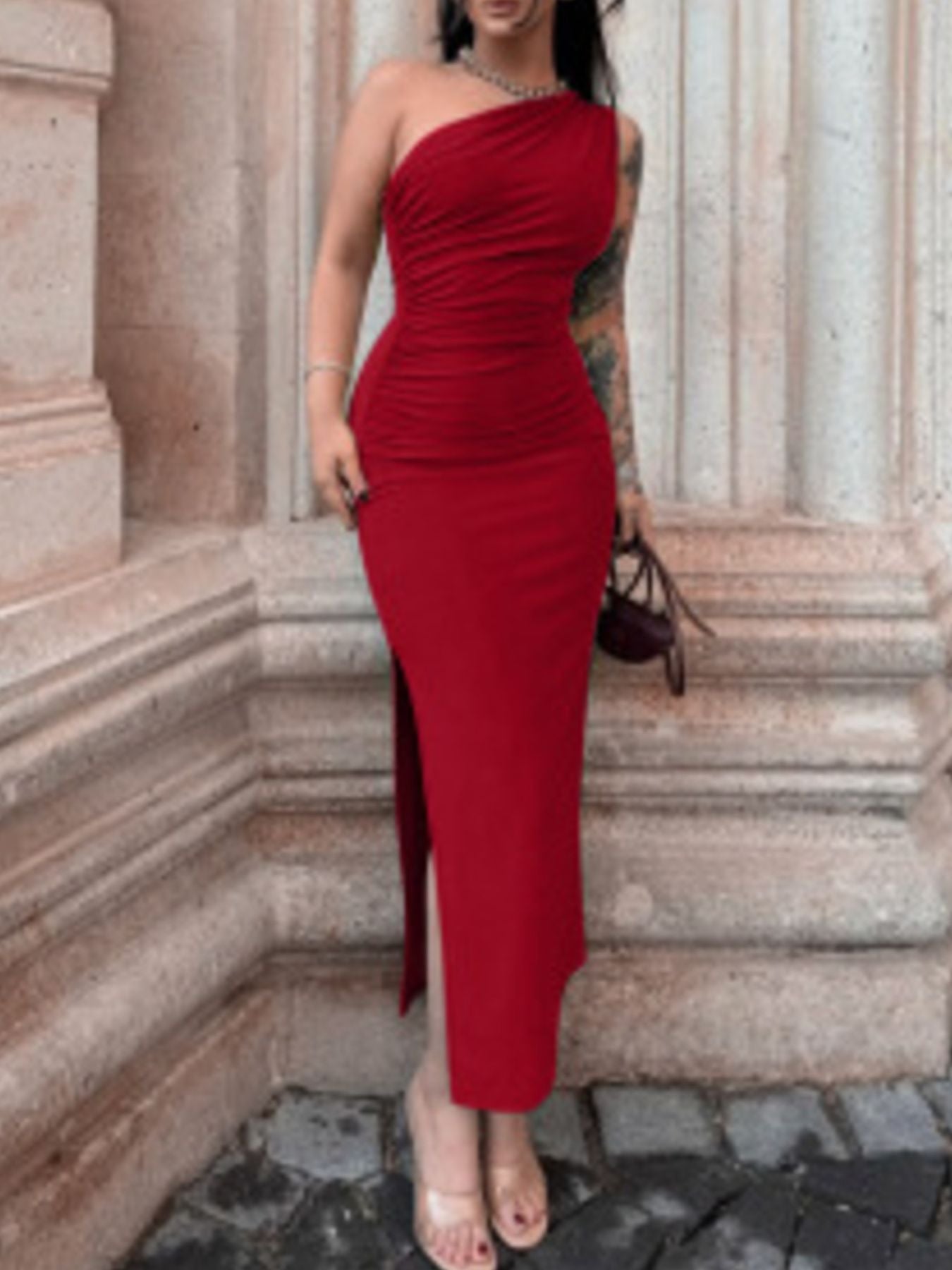 Deep red one-shoulder ruched bodycon dress with a high slit and subtle necklace.