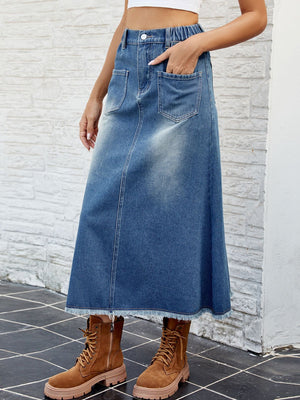 Faded blue denim midi skirt with frayed hem and front pockets.