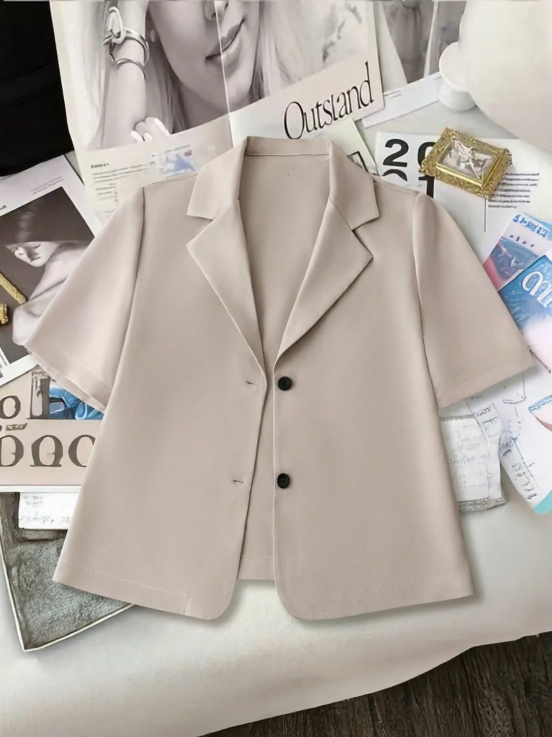 Light khaki short-sleeve tailored blazer jacket with two black buttons and notched lapels.