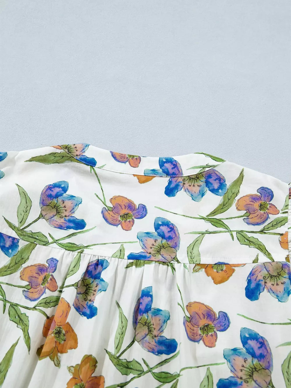 Cotton shirt with vibrant floral print, ruffled V-neck, and button detail.