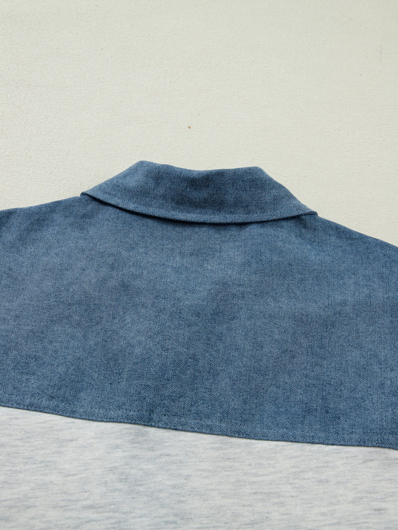 Two-tone denim polo shirt with classic collar and color-block detail.