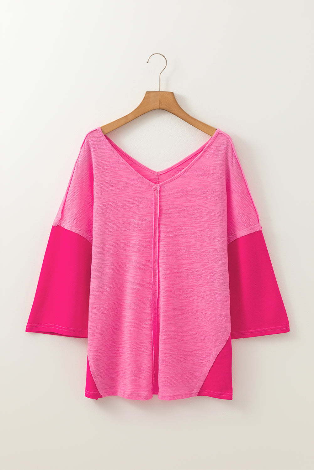 Hot pink v-neck blouse with contrast sleeves and textured fabric.