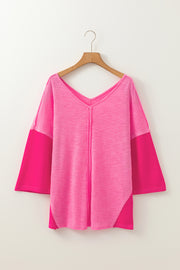 Hot pink v-neck blouse with contrast sleeves and textured fabric.