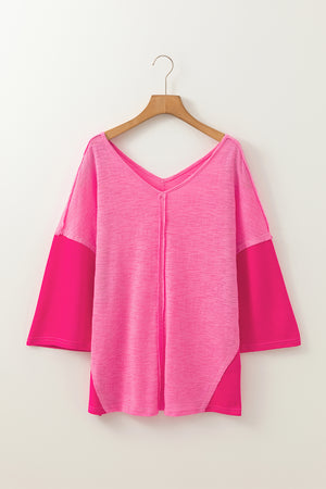 Hot pink v-neck blouse with contrast sleeves and textured fabric.