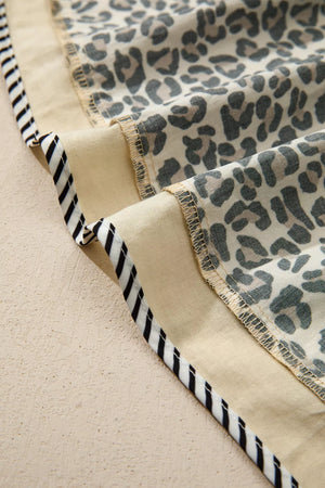 Leopard print mini dress with beige cotton blend fabric and black and white striped trim detail.