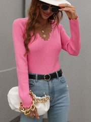 Pink ribbed knit top with scalloped neckline and long sleeves.