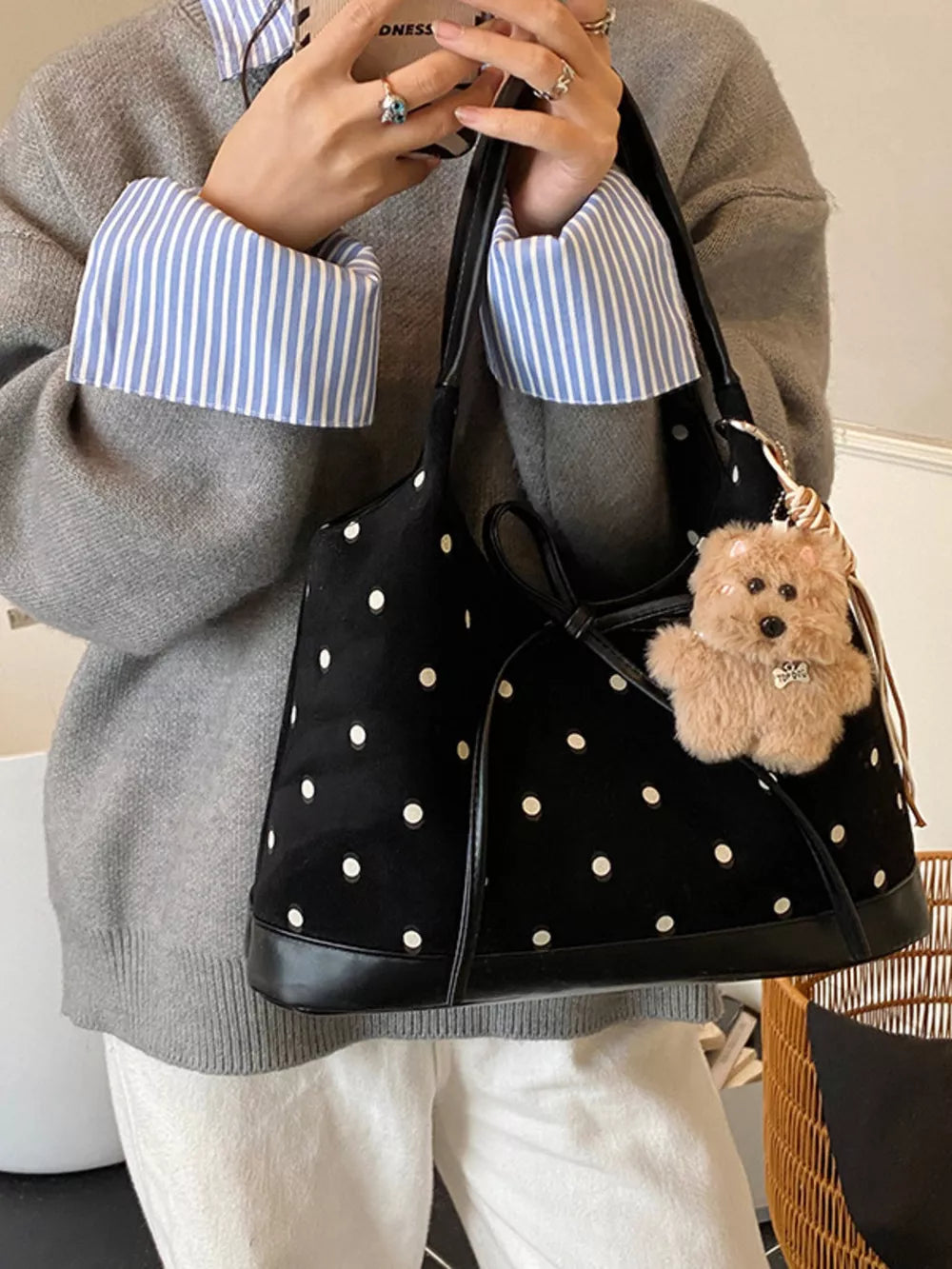 Black polka dot shoulder bag with bow detail and teddy bear charm.