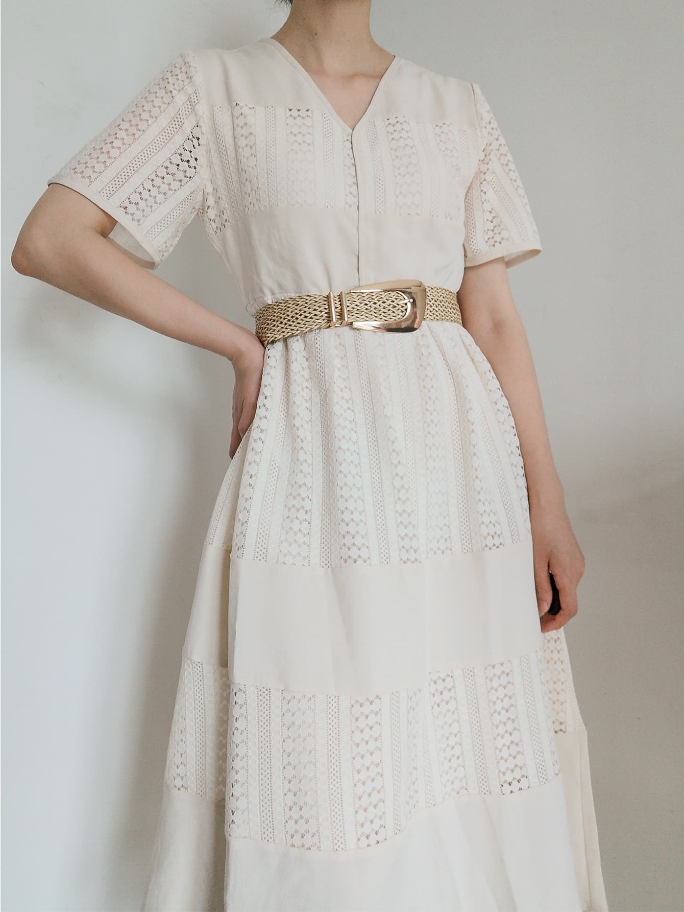 Woven raffia belt with gold-tone buckle, cinching a white lace dress.