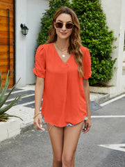 Textured orange v-neck blouse with ruched short sleeves and pleat-front detail