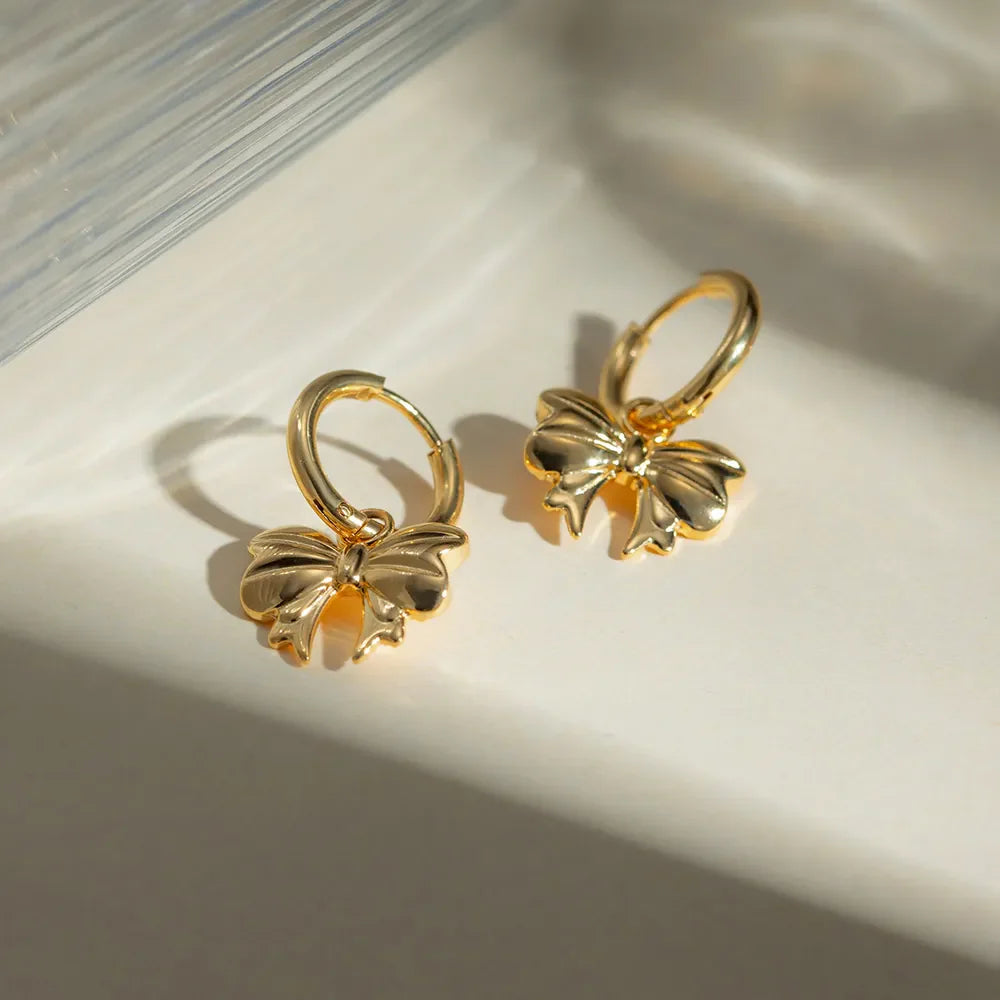 Gold hoop earrings with a detailed bow charm, 18K gold-plated.