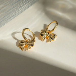 Gold hoop earrings with a detailed bow charm, 18K gold-plated.