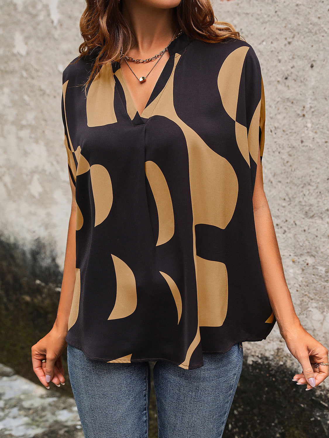 Black abstract print batwing blouse with V-neck and short sleeves.