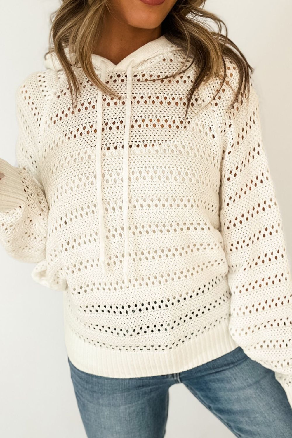 Openwork knit hoodie in beige with drawstring and long sleeves.