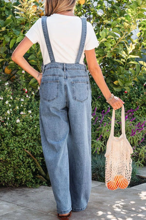 Denim wide-leg jumpsuit with buttoned front and adjustable straps, styled with a white tee.