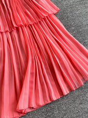 Pink pleated midi dress with tiered ruffle detail and spaghetti straps.