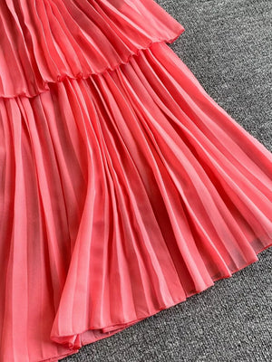Pink pleated midi dress with tiered ruffle detail and spaghetti straps.