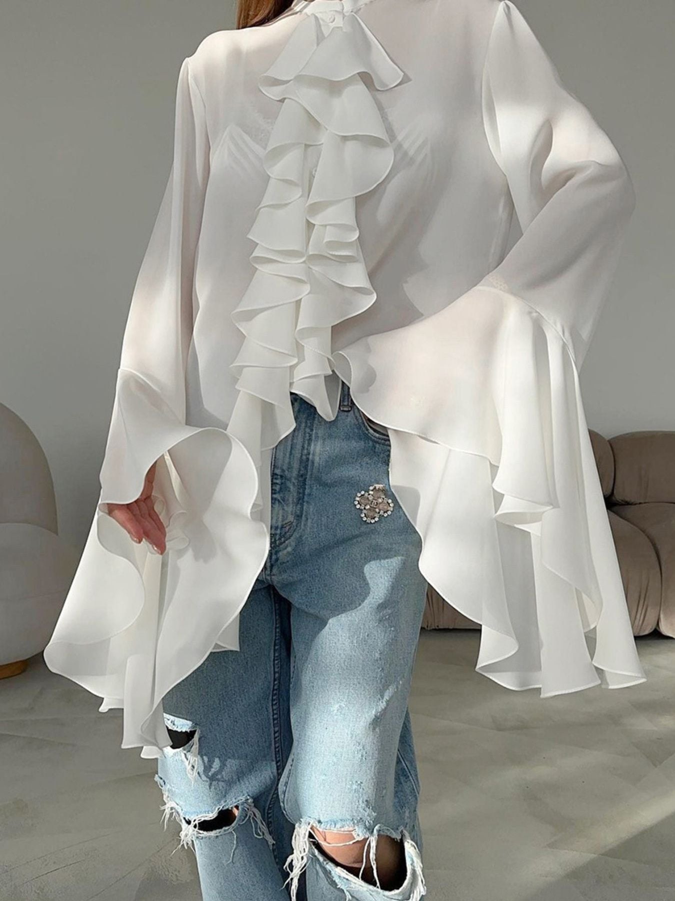 White ruffled flounce sleeve blouse with cascading ruffles and bell sleeves.