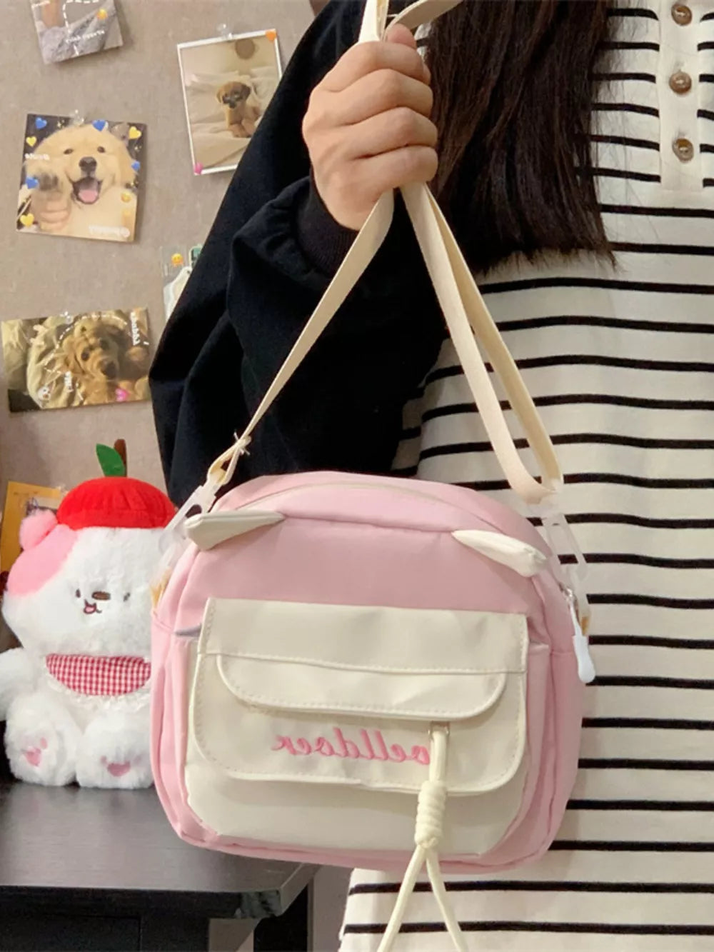 Pink crossbody bag with cat ears and dual front pockets, adjustable strap.