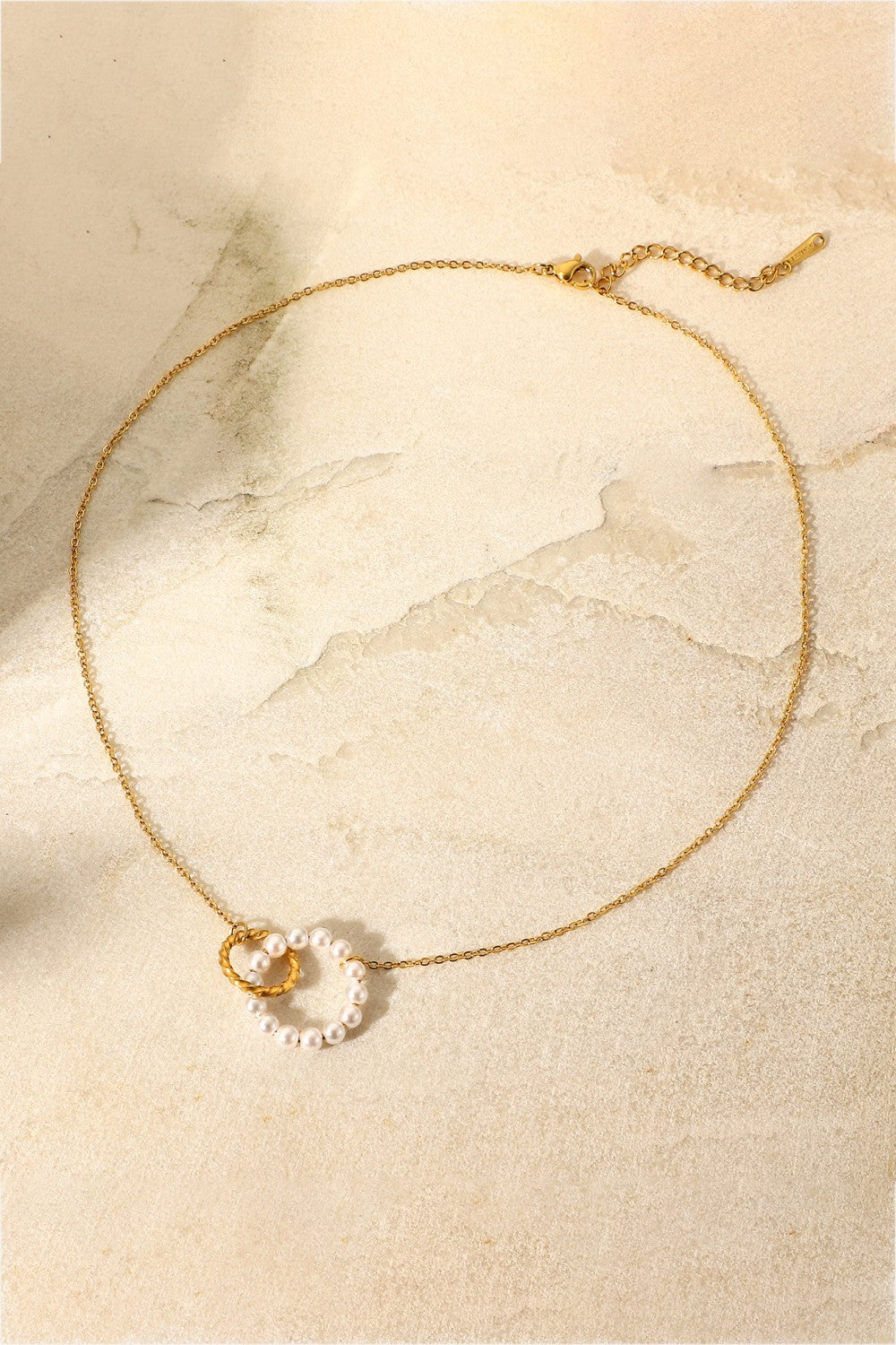 Gold necklace with interlocking pearl and twisted gold circles pendant