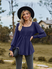 Navy peplum blouse with gathered yoke and smocked cuffs.