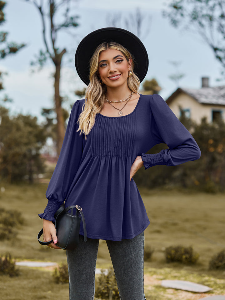 Navy peplum blouse with gathered yoke and smocked cuffs.