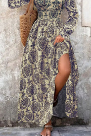 Maxi dress with bishop sleeves, cinched waist, and high slit in a navy damask print.