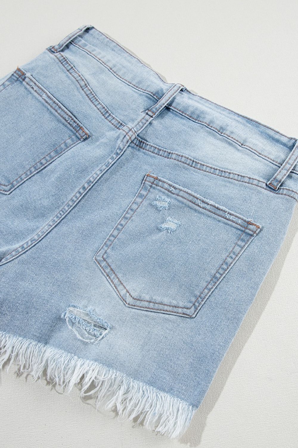 Light blue distressed denim cutoff shorts with frayed hem and ripped details.