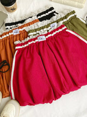 Mini skirt in red, orange, army green, and black with lace trim, gathered waist, and white side stripes.