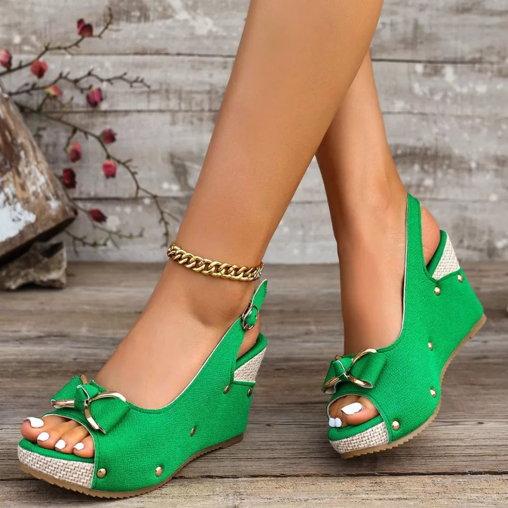 Green peep toe wedge sandals with decorative bow and adjustable strap.