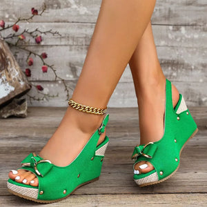 Green peep toe wedge sandals with decorative bow and adjustable strap.