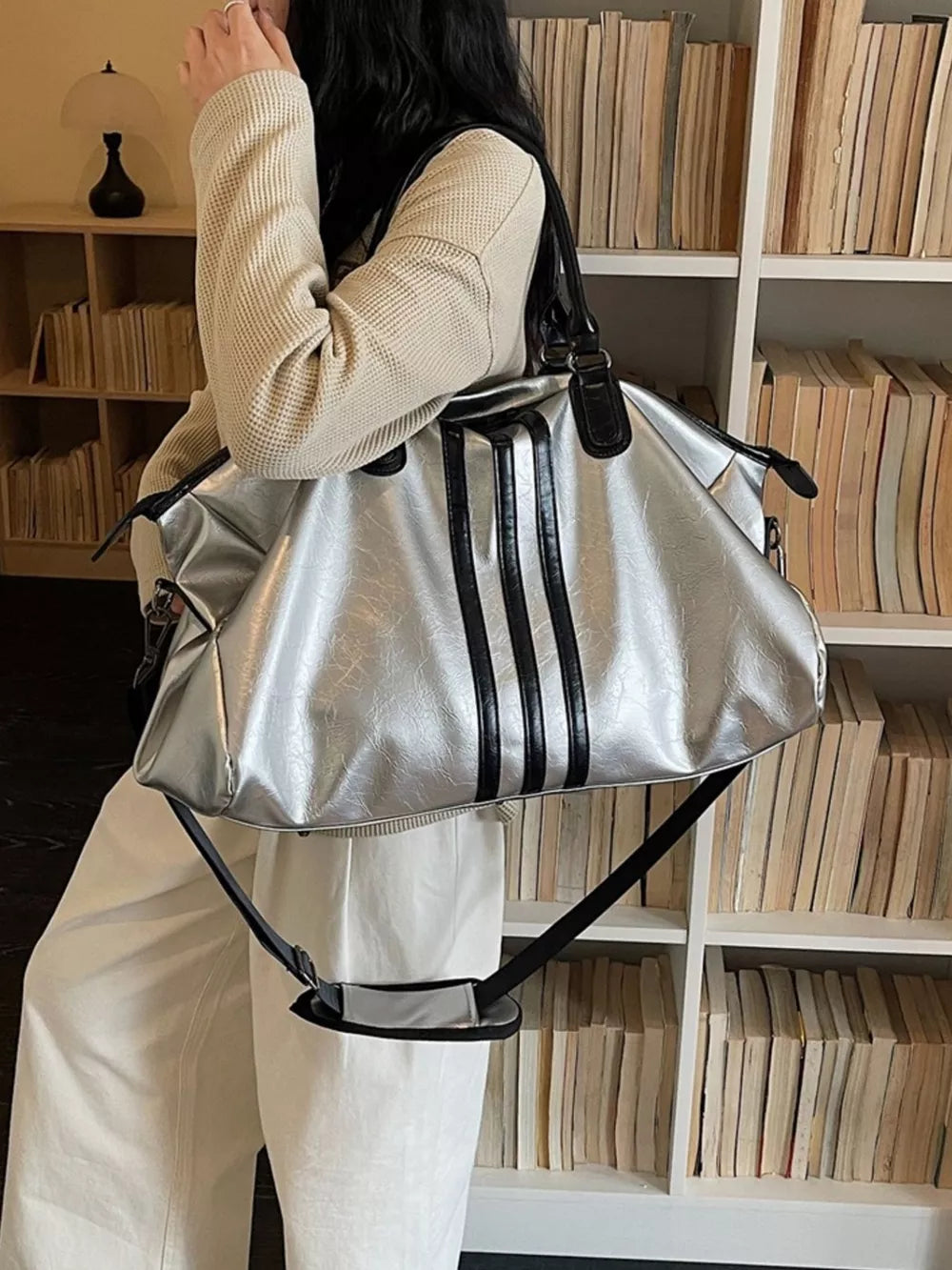 Sleek metallic silver duffle bag with black stripes and shoulder strap.