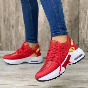 Red lace-up chunky platform sneakers with gold accents and glitter detail.