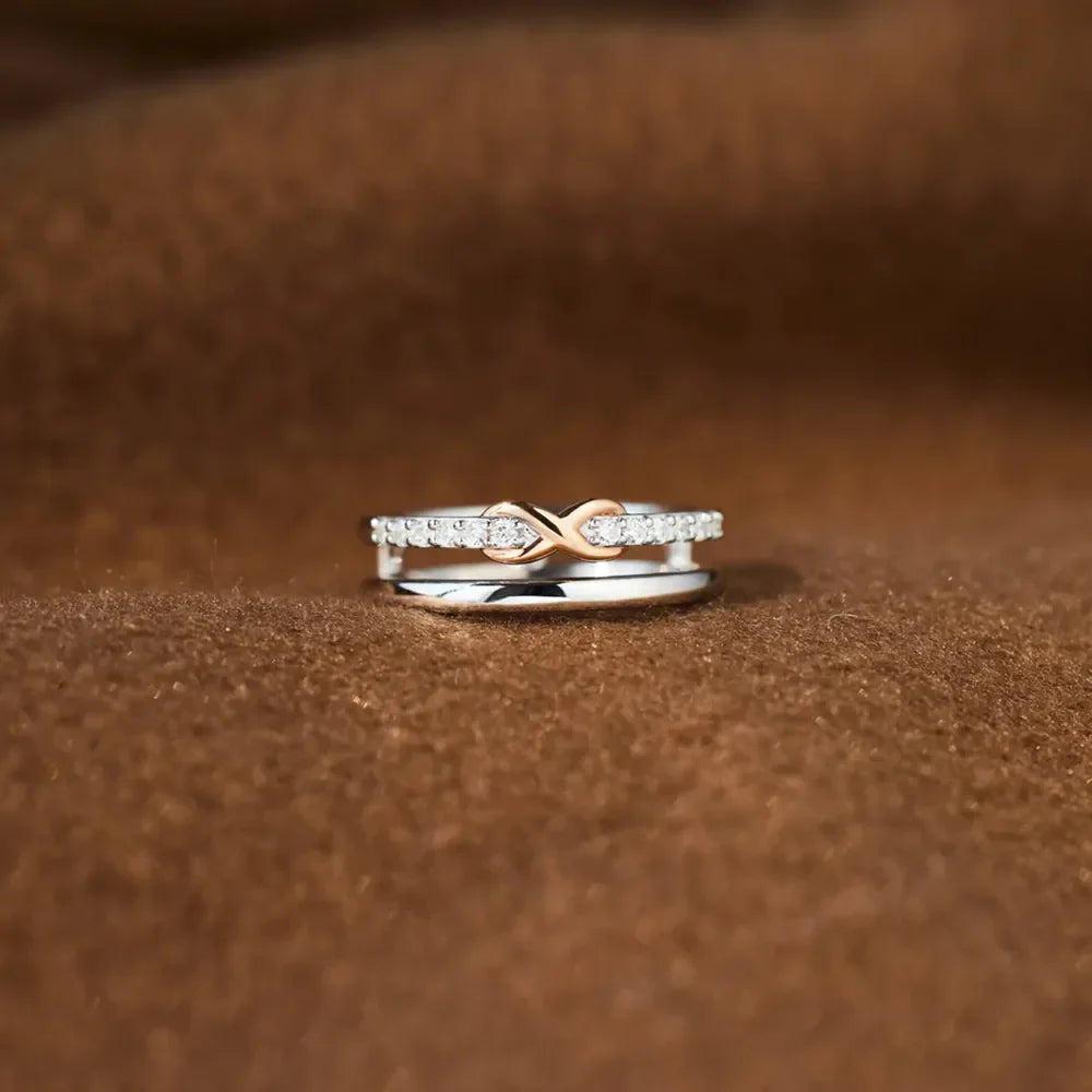 Silver infinity knot ring set with diamonds on a brown textured background