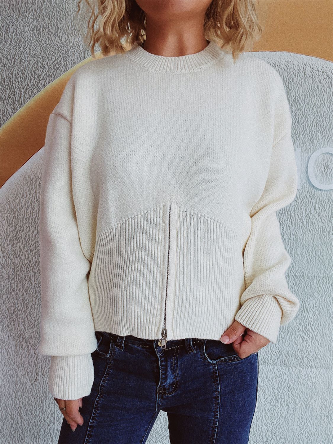 White knit zip-front sweater with ribbed hemline and crew neck.