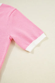 Pink knit top with white contrast trim on short sleeves.