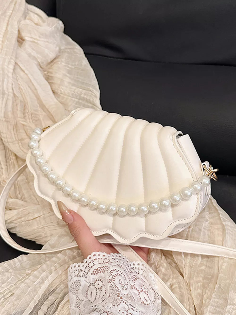 White shell crossbody bag with pearl trim and quilted detail.