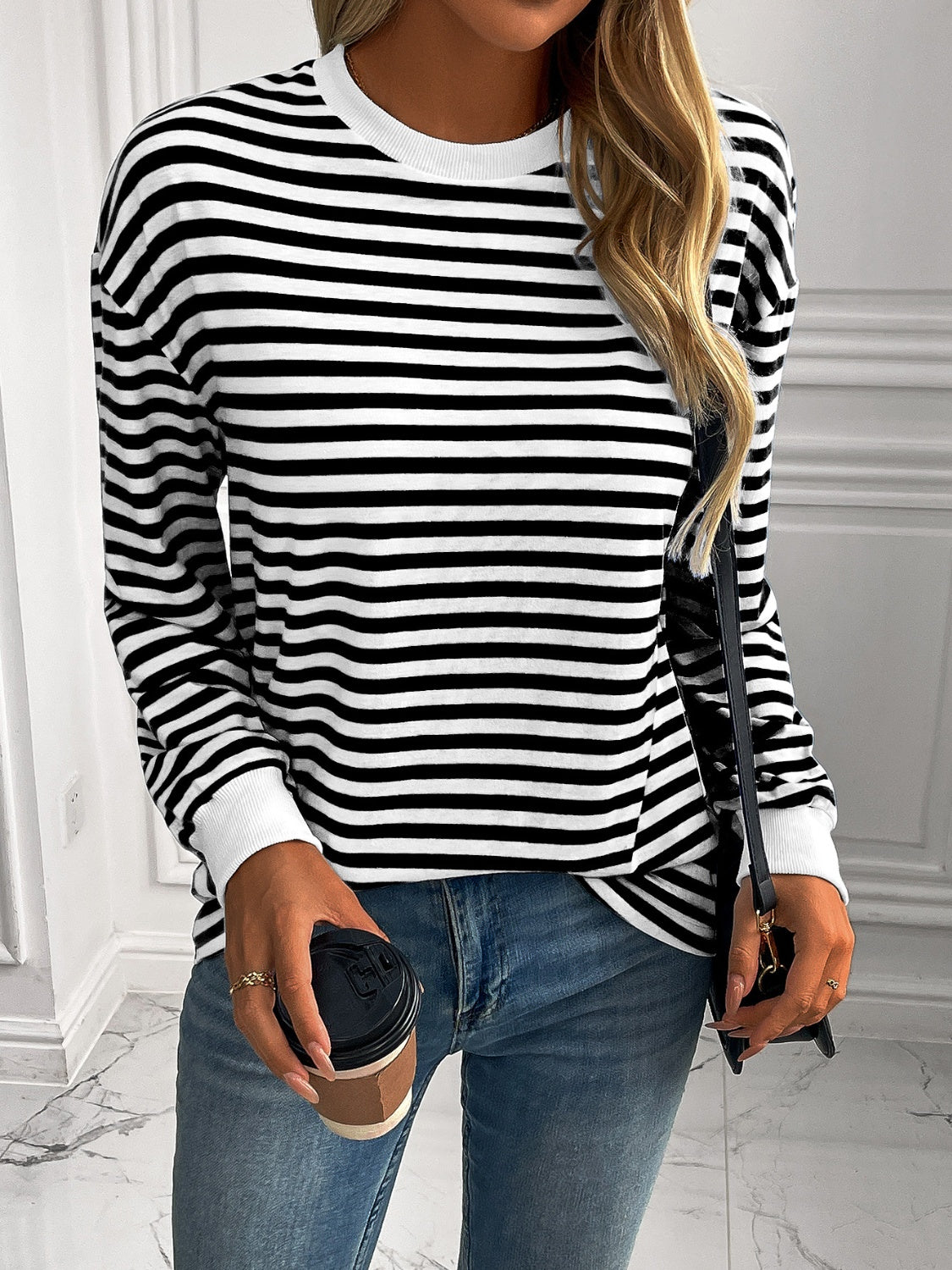 Black and white horizontal stripe crewneck sweatshirt with white cuffs.