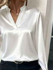 White satin maternity blouse with notched V-neck and long sleeves, styled with a necklace.