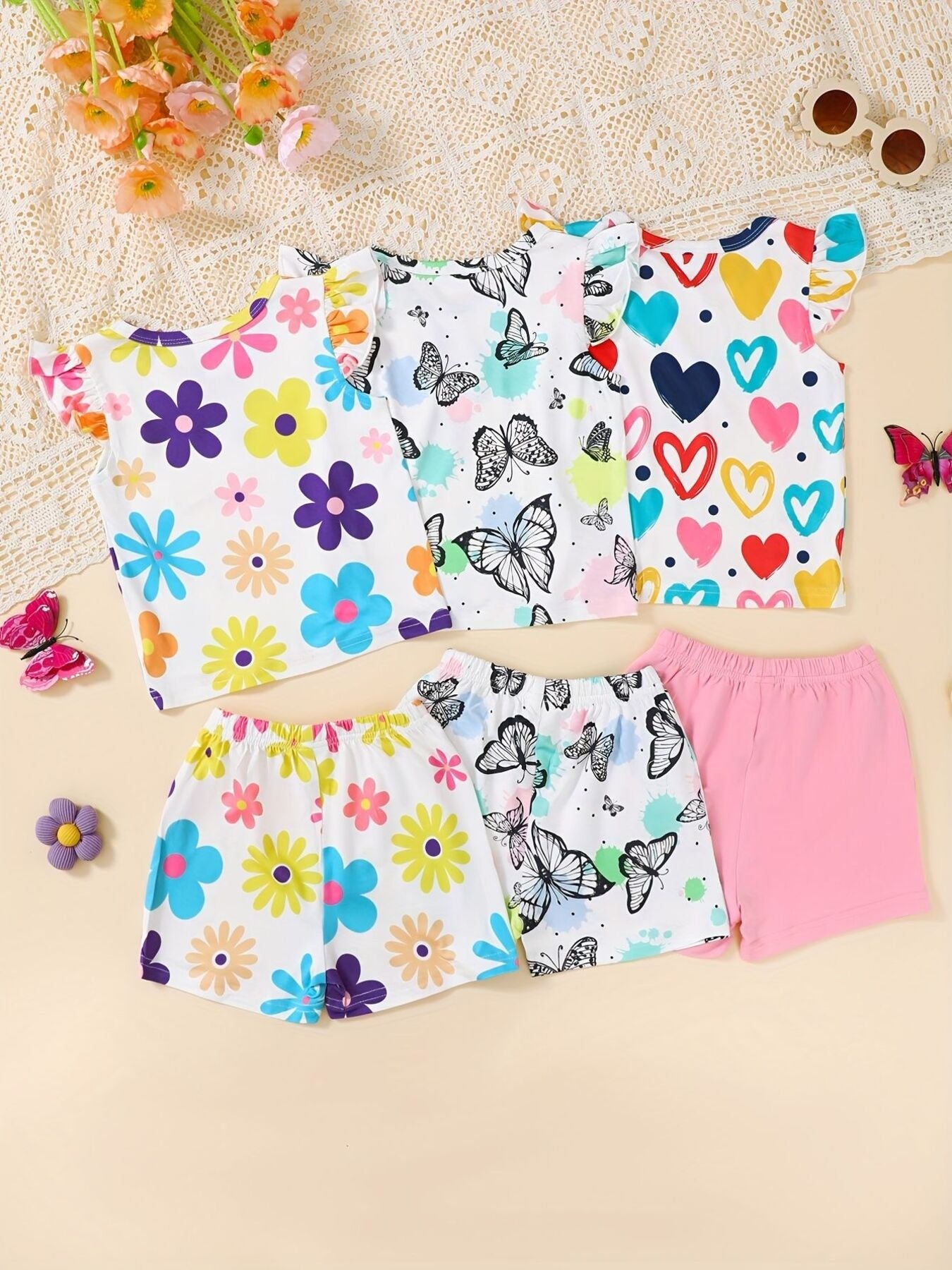 Baby shorts and tops with butterfly, flower, and heart prints.