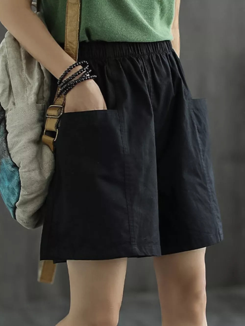 Black chino shorts with elastic waist and side pockets, styled casually.