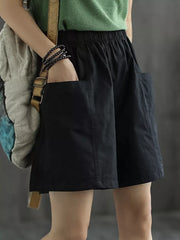 Black chino shorts with elastic waist and side pockets, styled casually.