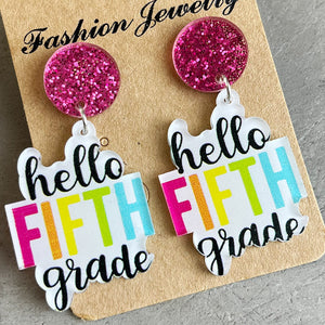 Acrylic drop earrings with pink glitter tops and "hello FIFTH grade" text in bright colors.