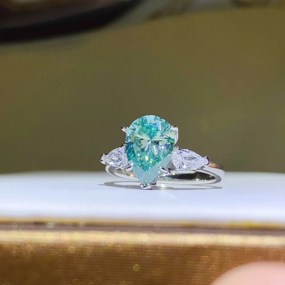 Silver ring with a large teardrop moissanite and two pear-cut stones.
