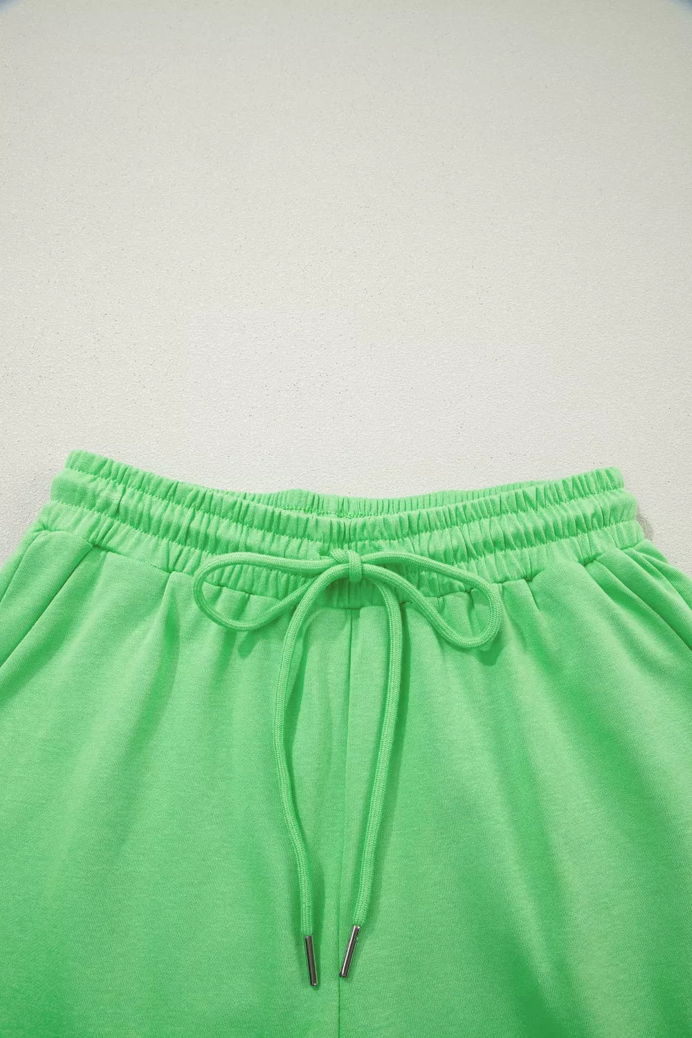 Green cotton drawstring shorts with elastic waistband and silver-tipped ties.