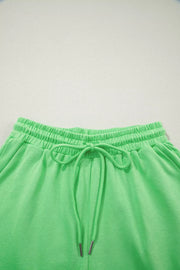 Green cotton drawstring shorts with elastic waistband and silver-tipped ties.