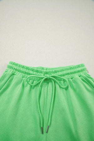 Green cotton drawstring shorts with elastic waistband and silver-tipped ties.